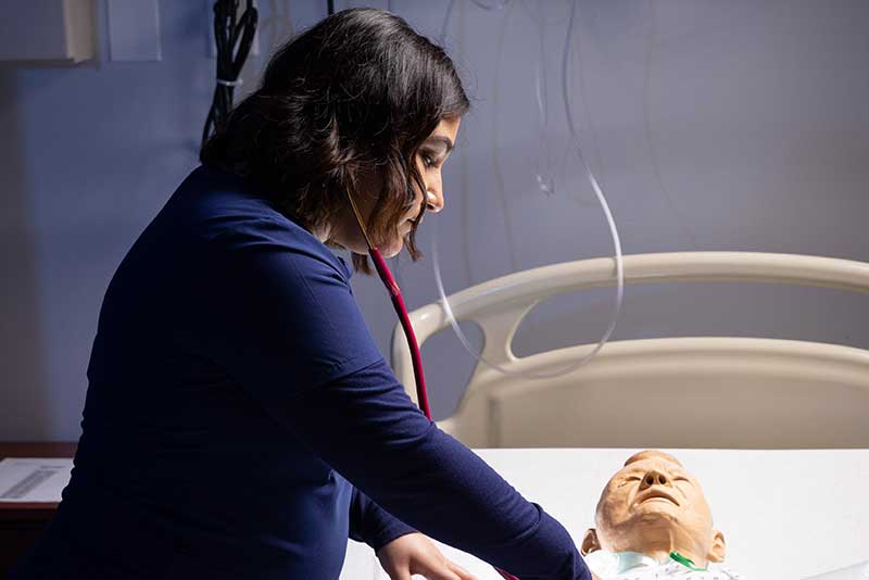 ABSN student working with simulation manikin