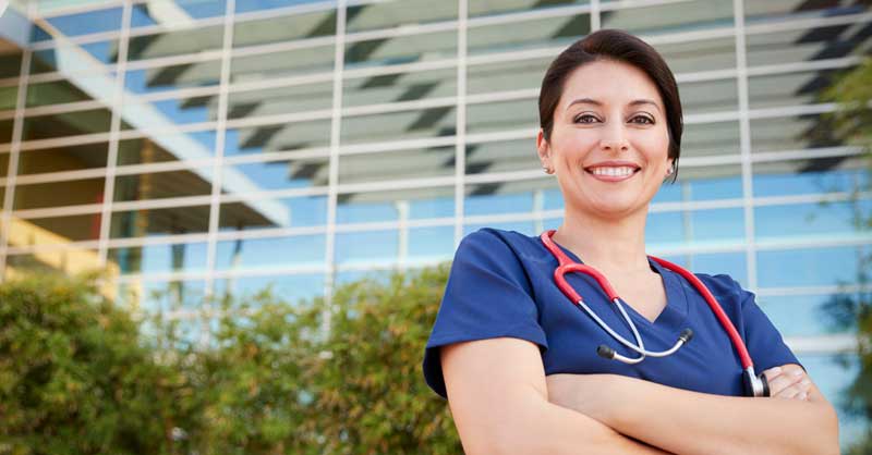 Nurse wearing blue scrubs standing outside