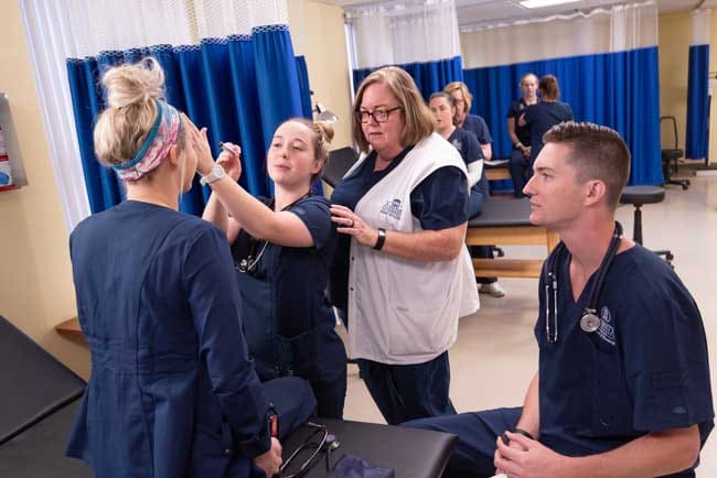 Averett ABSN instructor working with students in skills lab