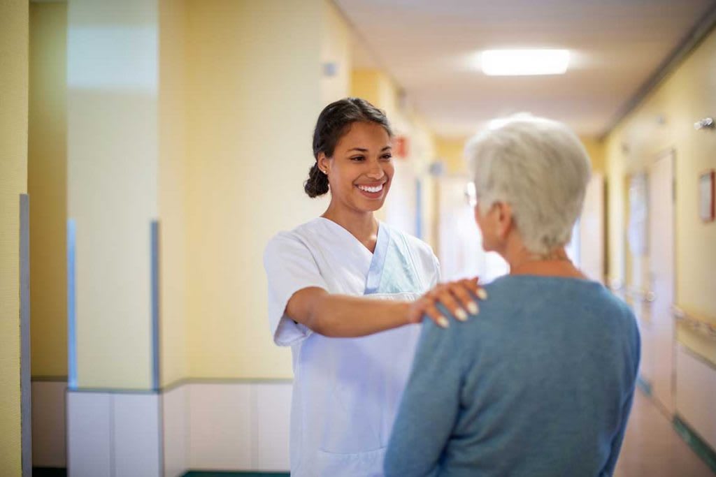 nurse putting hand on elderly patient's shoulder