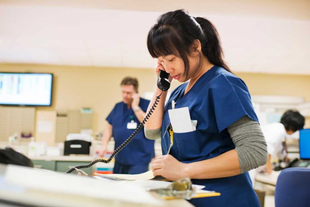 Nurse on phone reviewing paperwork