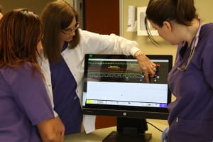 Nursing instructor explaining vital metrics on a monitor