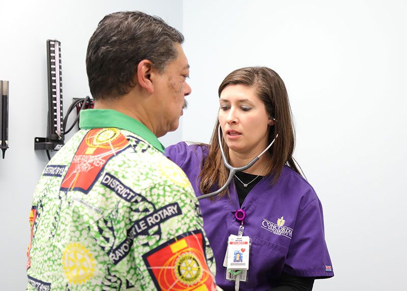 Nursing student using stethoscope to listen to patient's heartbeat