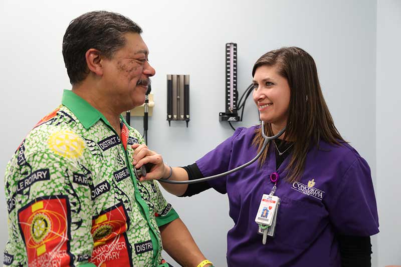 nursing student using stethoscope to check patient heartbeat