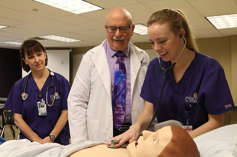 Nursing instructor with nursing students working with simulation manikin