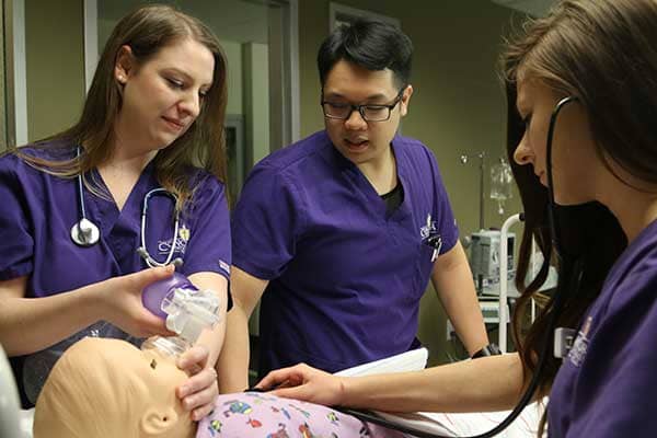 Three nursing students with pediatric simulation manikin