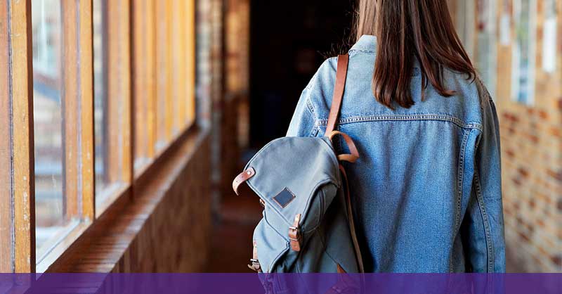 Woman walking down hallway with backpack