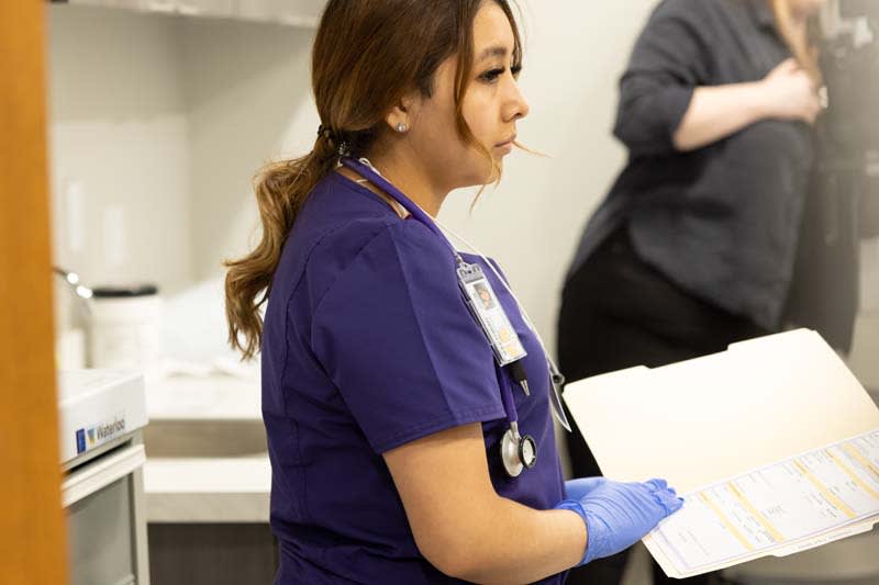 ABSN student in sim lab holding chart folder