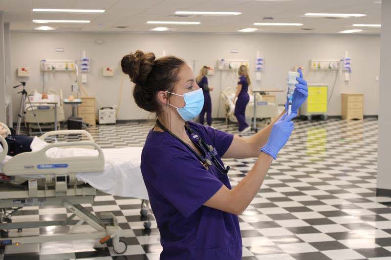 CTX ABSN student standing in lab using a syringe