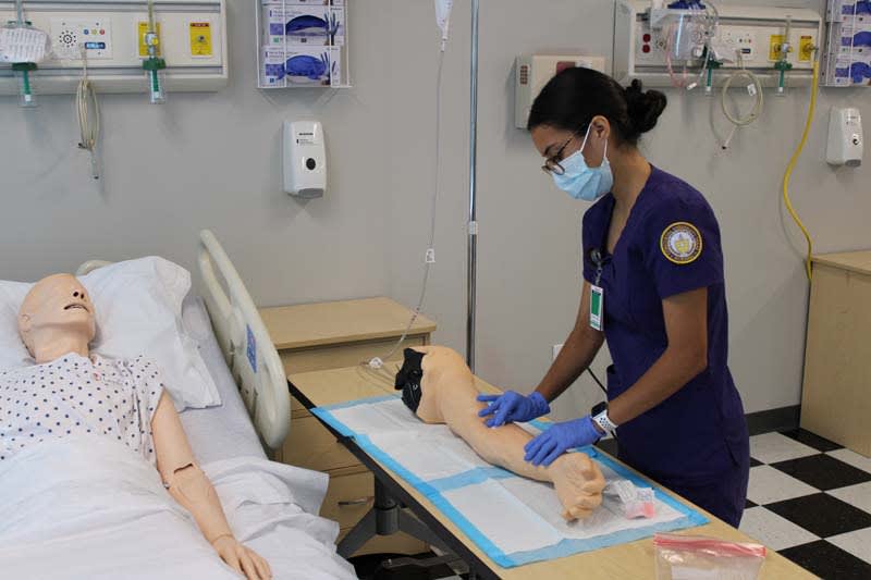 ABSN student working with simulation manikin arm