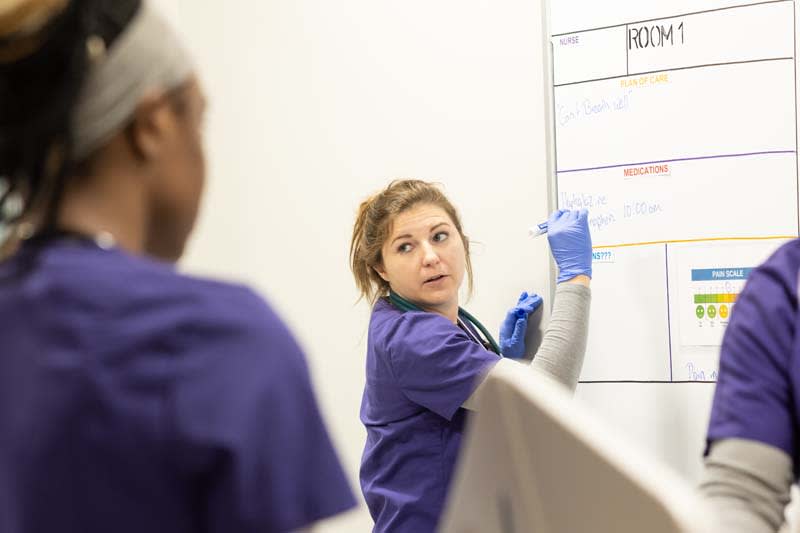 ABSN student writing on dry erase board