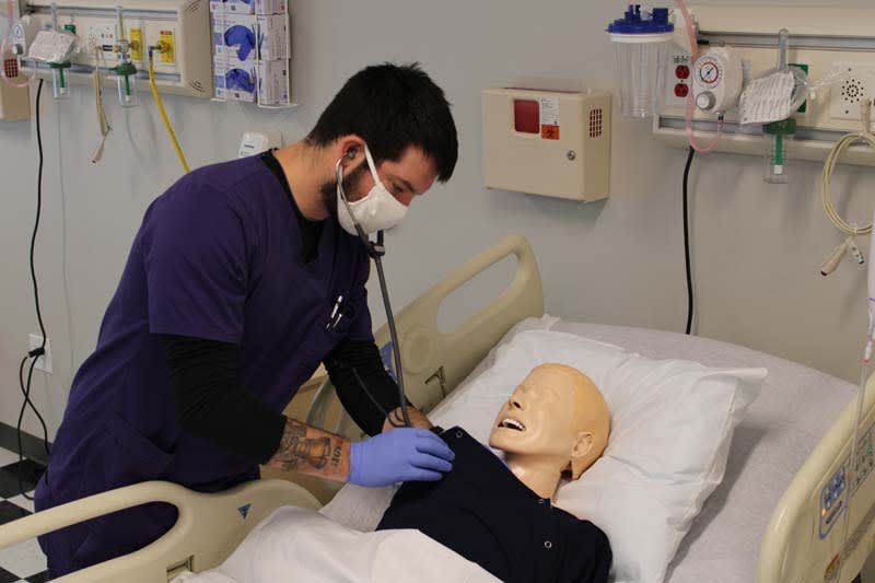 ABSN student working with sim manikin