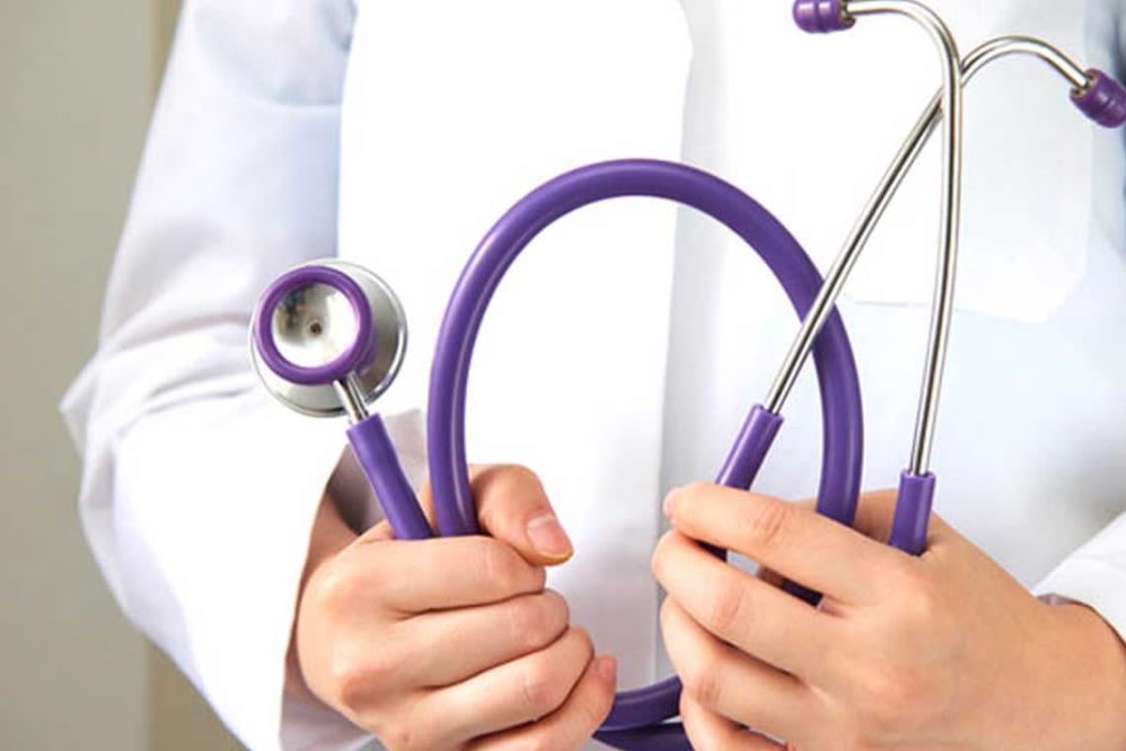 close up of person in white coat holding purple stethoscope