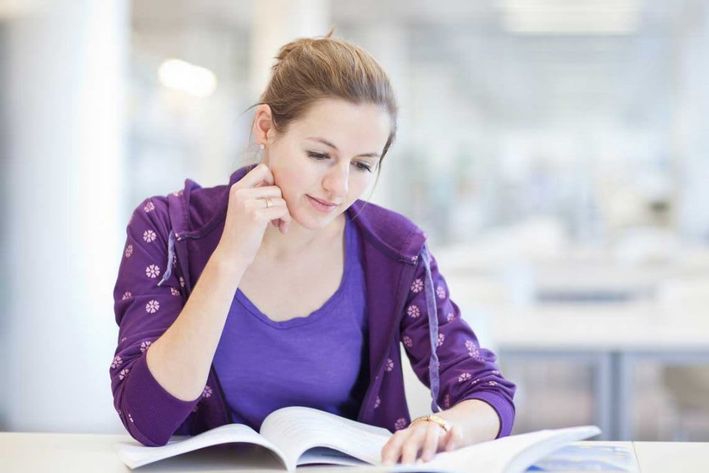 woman wearing purple sitting at desk with books