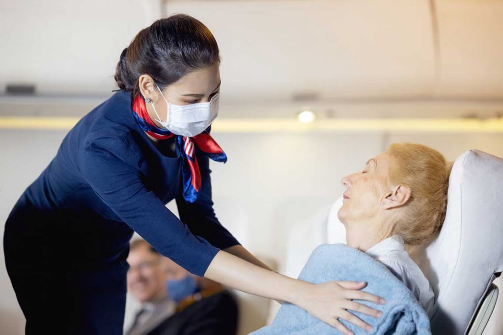 nurse on plane giving elderly woman a blanket