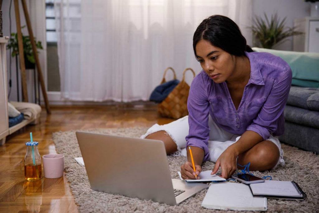 person with laptop and notebooks sitting on floor