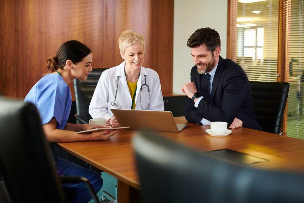 nurse sitting with two people at table