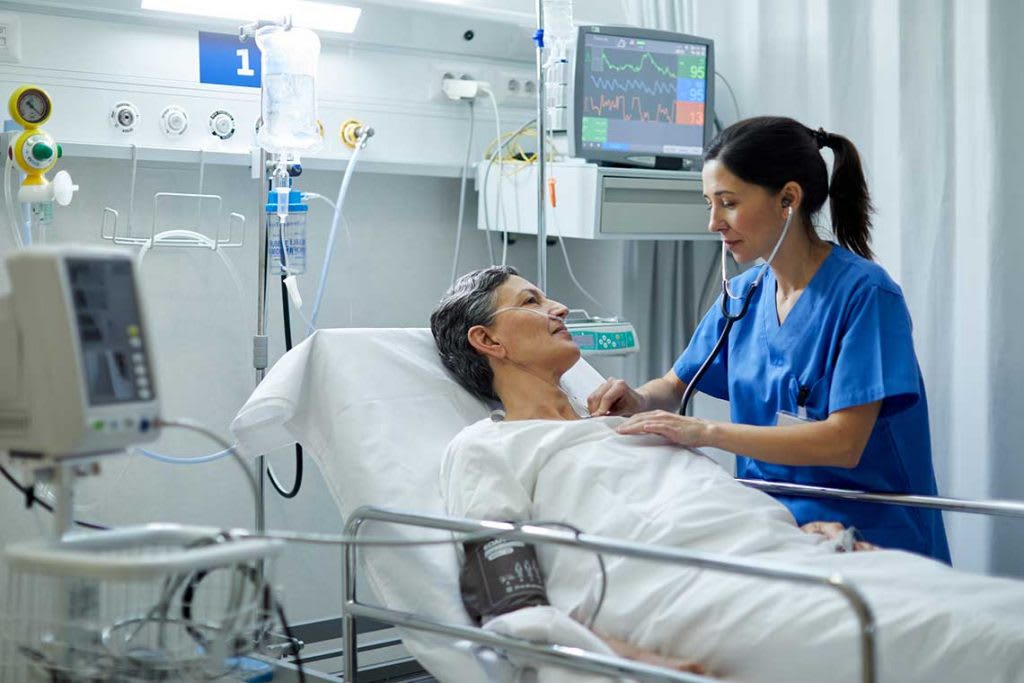 nurse helping patient in patient bed