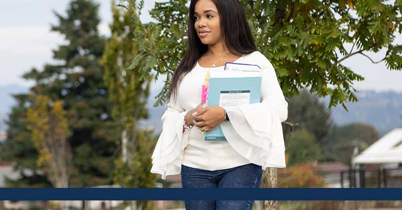 Student walking outside holding books