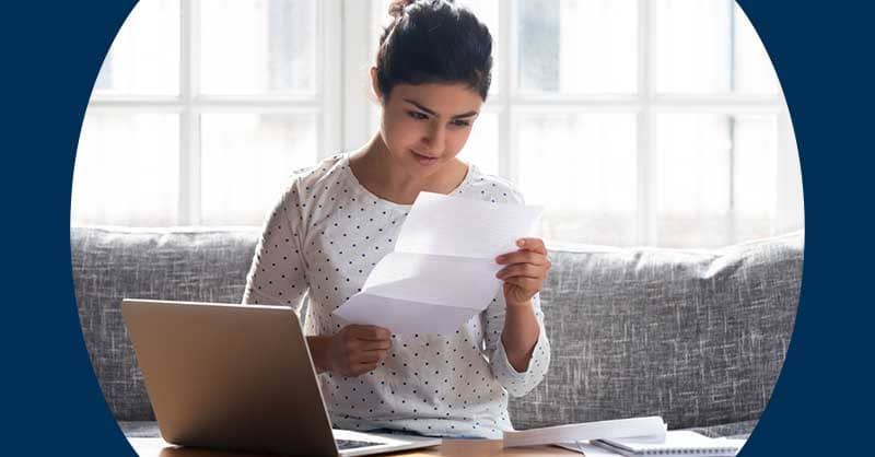 Woman sitting at desk with paper and a laptop