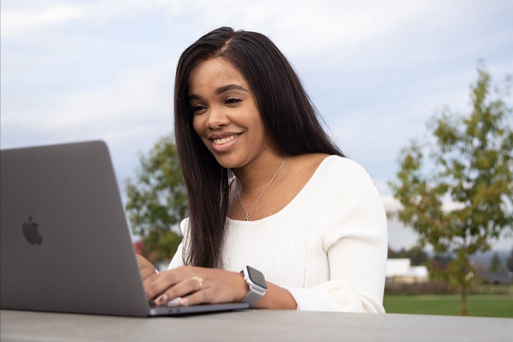 student sitting outside using laptop