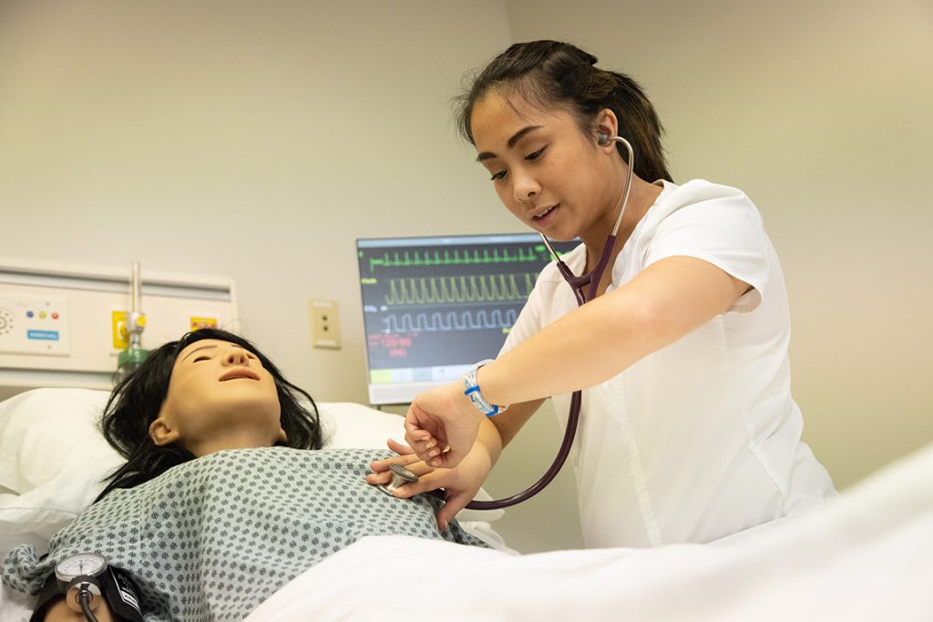 nursing student working with simulation manikin