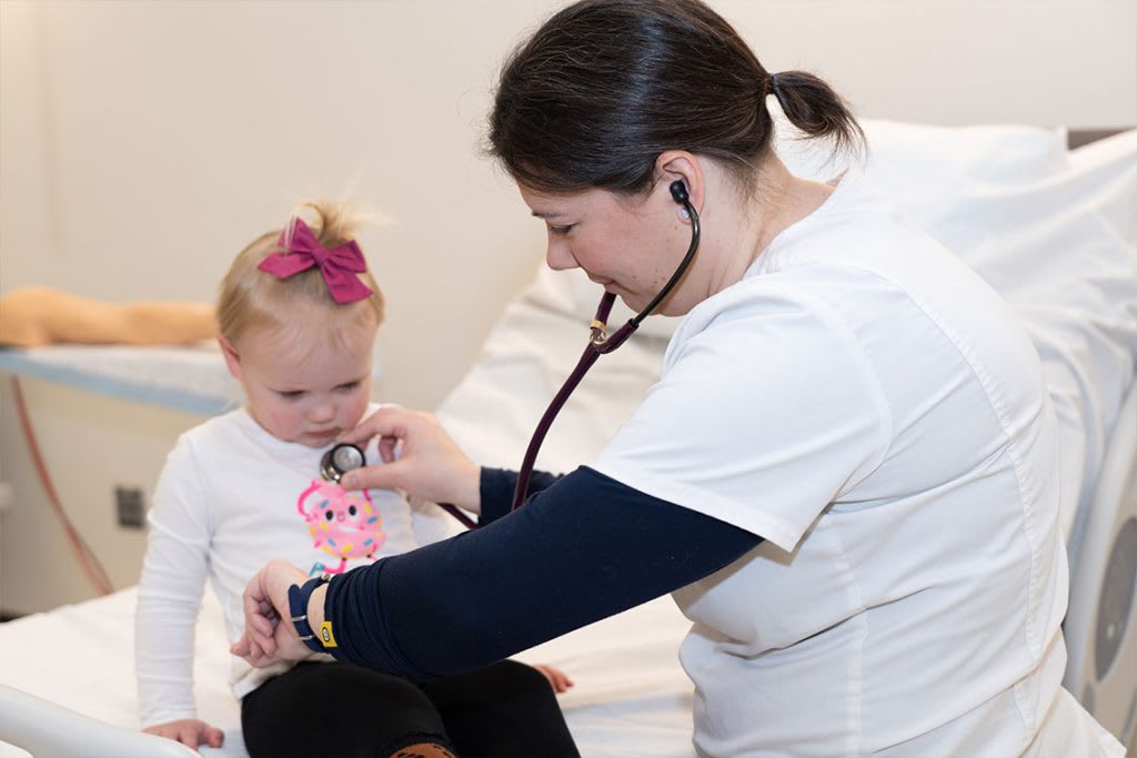 nurse using stethoscope to hear child's heartbeat