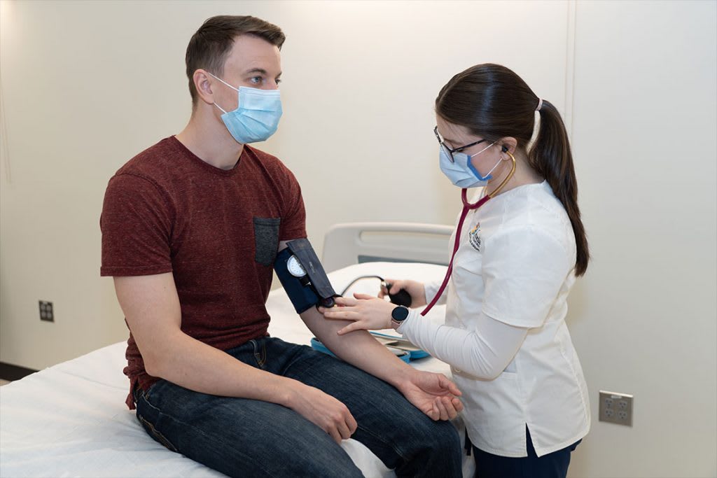 nursing student testing man's blood pressure with blood pressure cuff