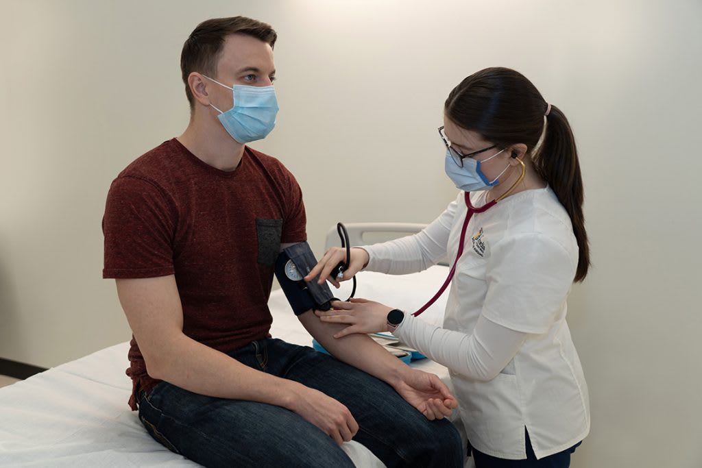 nursing student testing man's blood pressure with blood pressure cuff