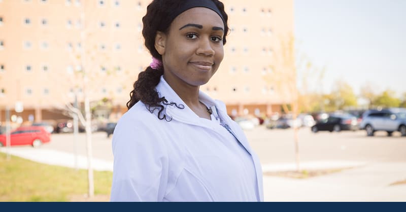 CSP ABSN student standing outside in white coat