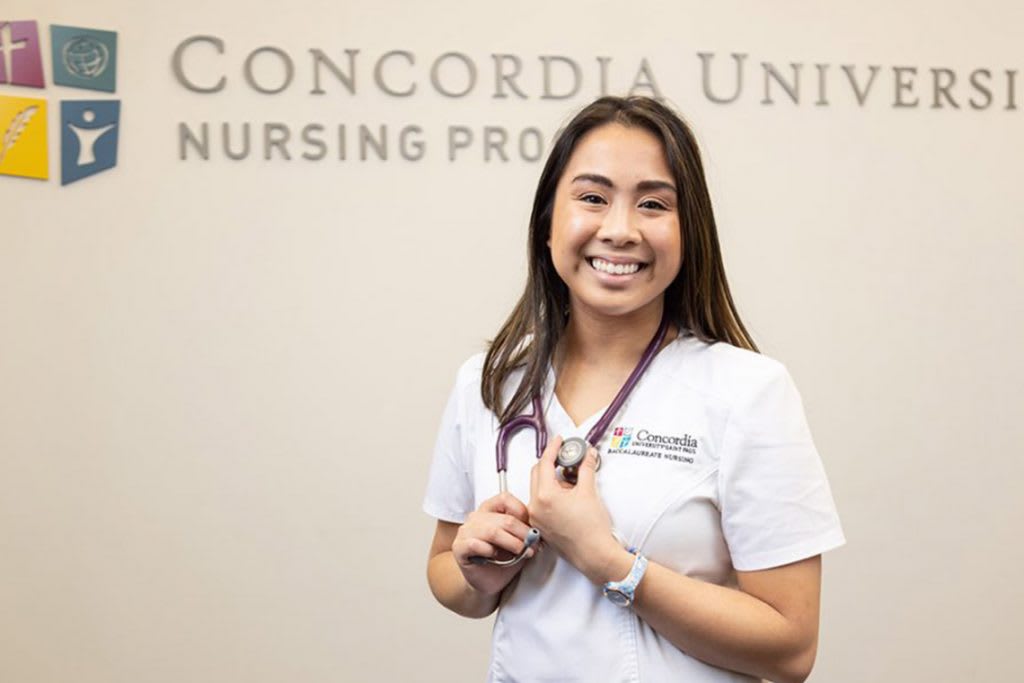 Concordia St. Paul ABSN student standing in front of university logo