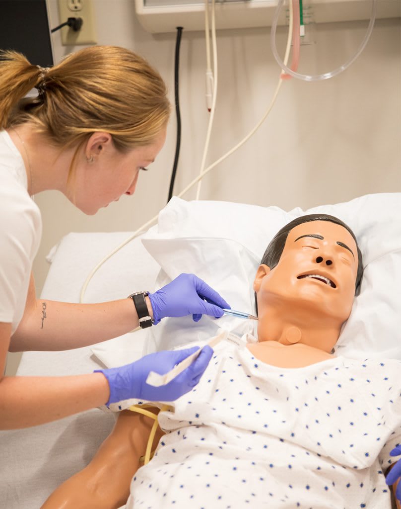 nursing student working with a sim manikin