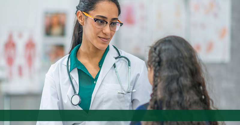 Nurse in green scrubs and lab coat with patient