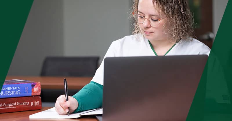 Nursing student working on laptop and taking notes