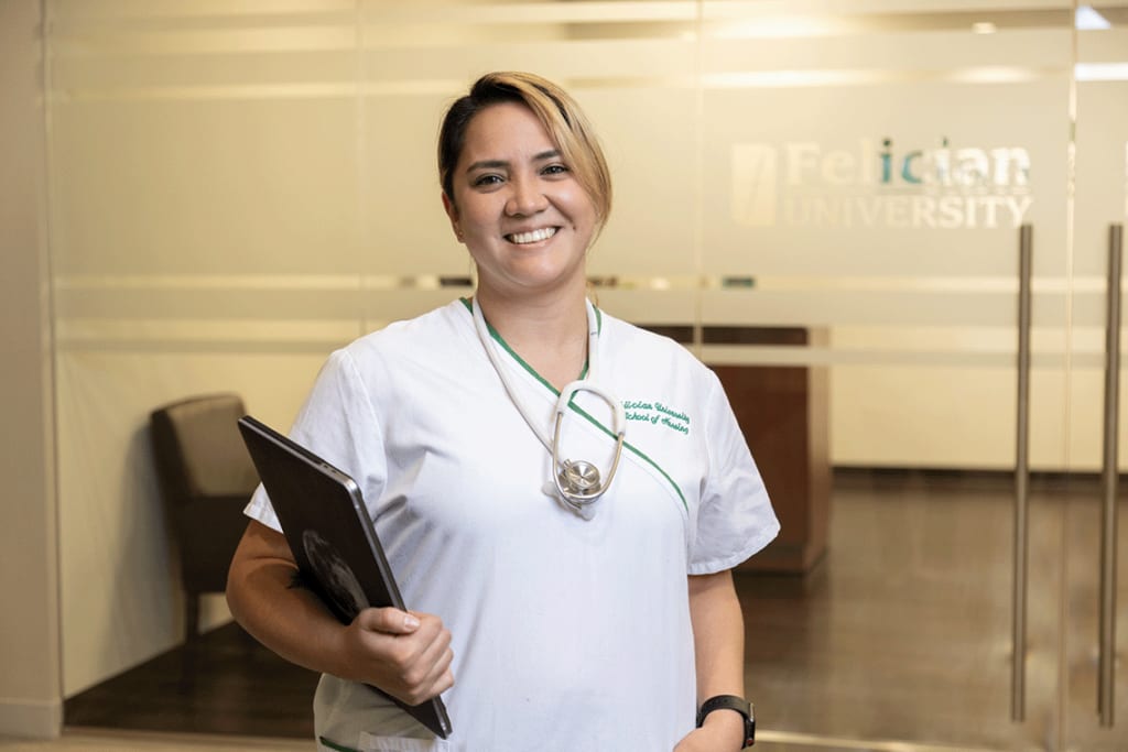 Felician ABSN student smiling and holding laptop