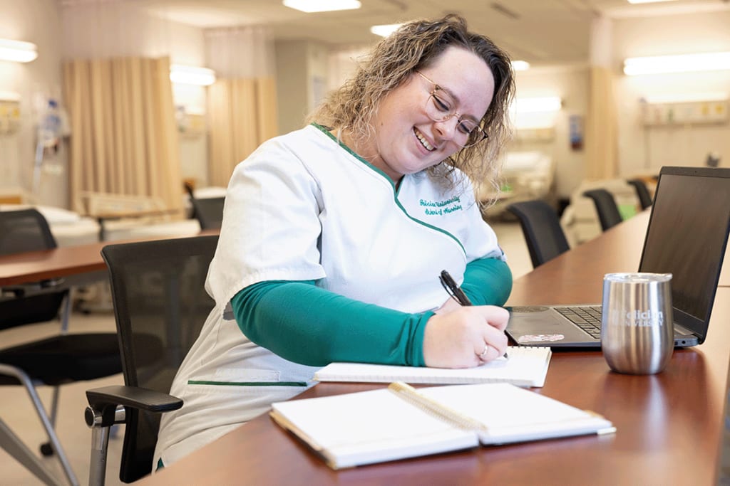 Felician ABSN student sitting at desk writing in notebook