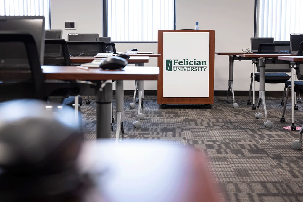 desks and chairs with laptops in classroom