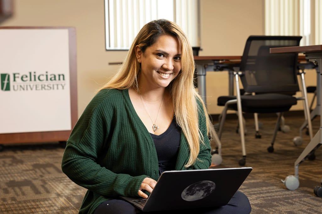 Felician nursing student sitting on floor using laptop