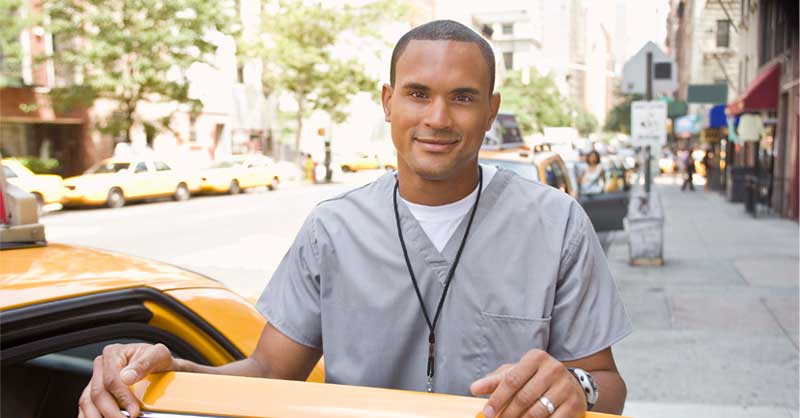 Male nurse standing outside holding open door of taxi