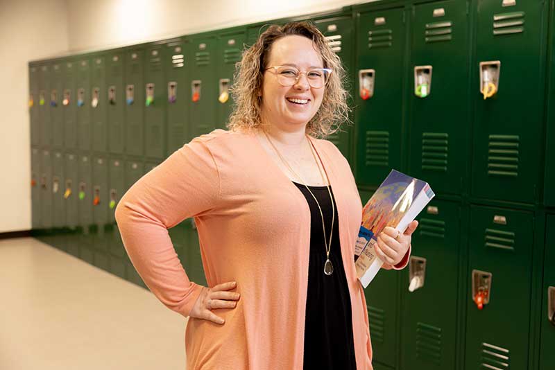 ABSN student holding books by lockers