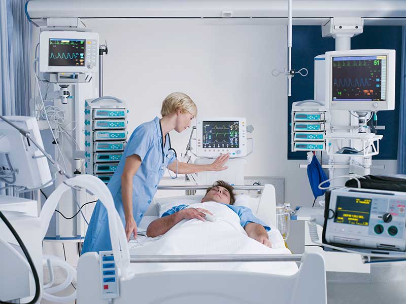 nurse tending to ICU patient in hospital bed