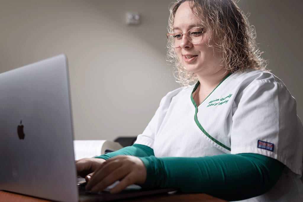 Felician ABSN student sitting and using laptop