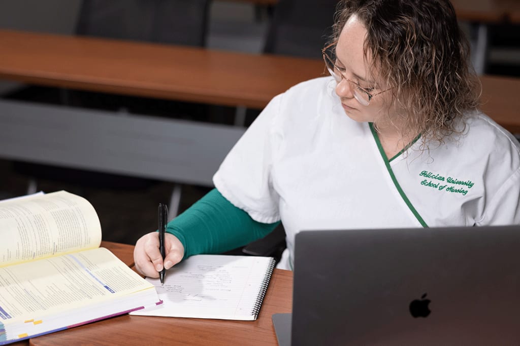 Felician nursing student writing notes in notebook