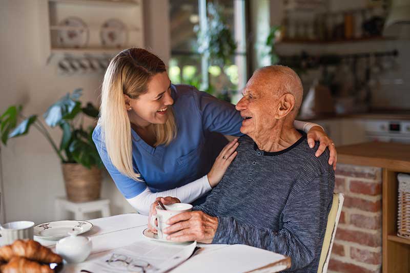 nurse with elderly patient in home kitchen