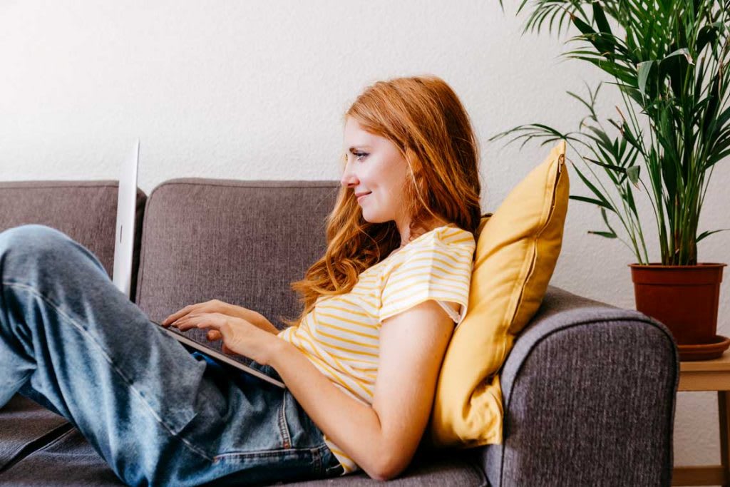 woman sitting on couch with laptop