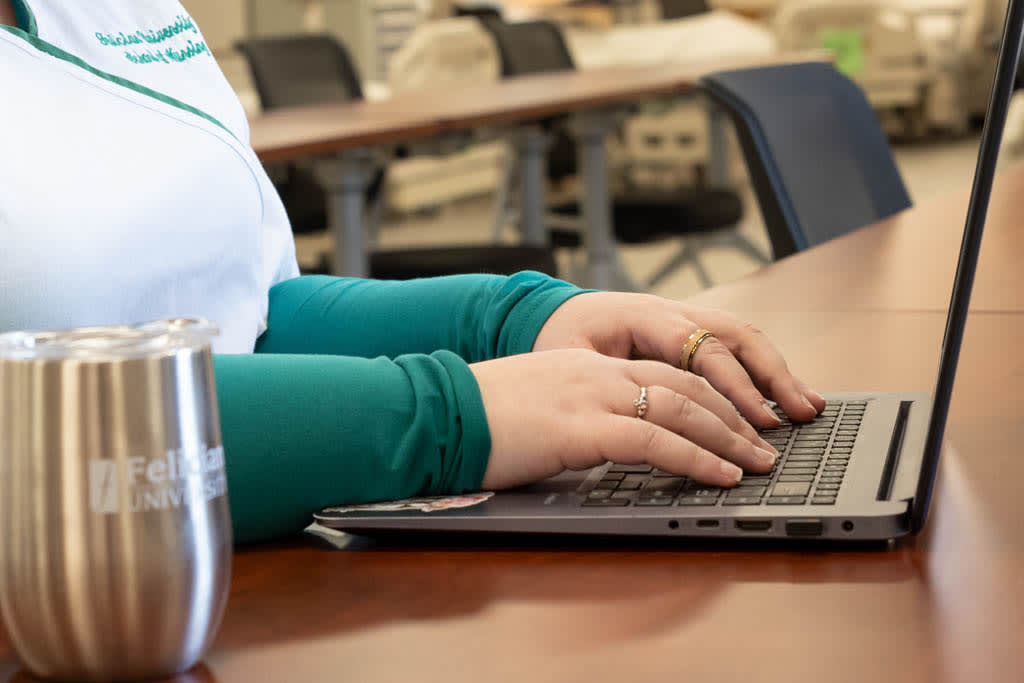 Hands on laptop with felician mug