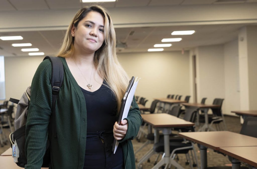 student with back pack and laptop looking at camera