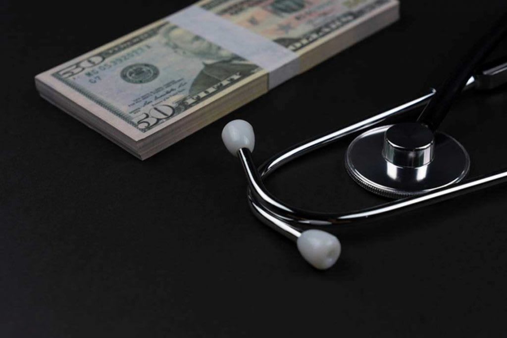 stethoscope with stacked money beside it