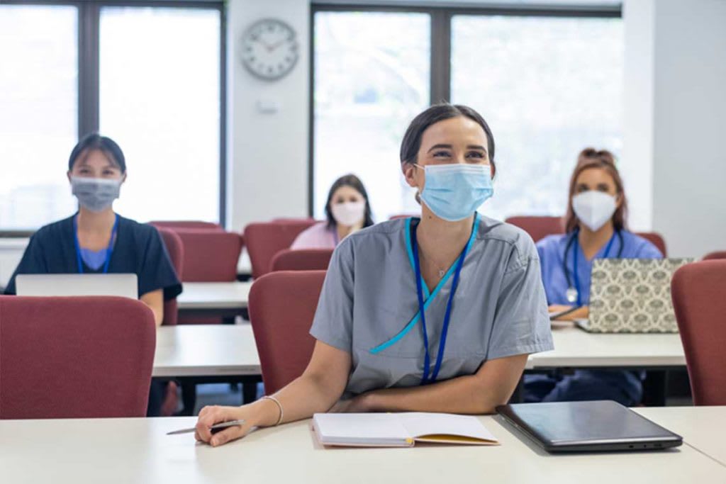 nurses wearing face masks sitting in classroom