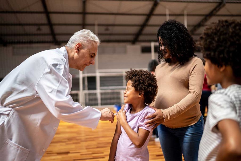 doctor giving shots to patients in homeless shelter